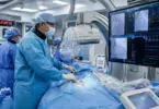 Interventional cardiologist performing a cardiac catheterization procedure in a modern cardiac catheterization laboratory.