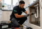 Professional plumber carrying out maintenance work in a social housing property in Ealing, London.
